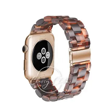 Amber and brown tortoiseshell-patterned linked Apple Watch band with a gold-tone clasp, shown on a watch