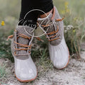 Beige duck boots with light glossy rounded toes, contrasting neutral uppers, and tan laces