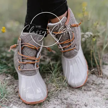 Beige duck boots with light glossy rounded toes, contrasting neutral uppers, and tan laces