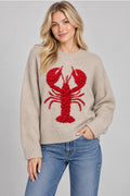 Beige long-sleeve knit sweater with a large textured red lobster, dropped shoulders, and ribbed neckline, cuffs, and hem