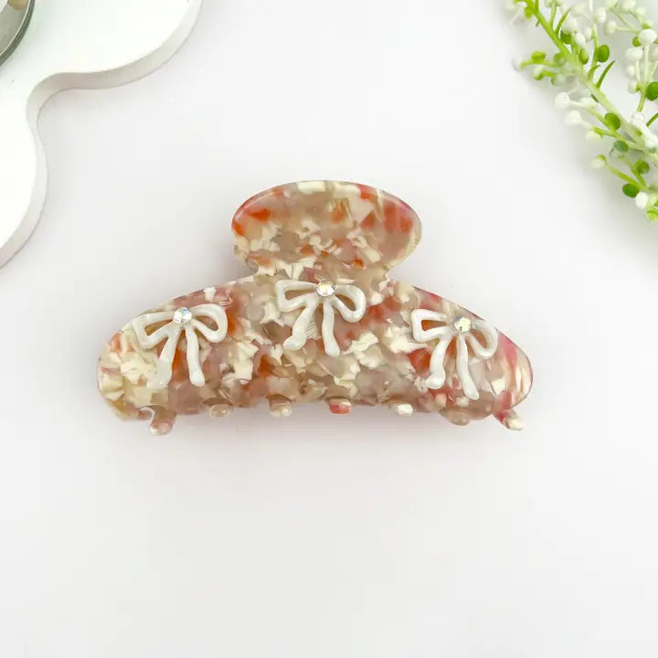 3D Studded Bow Claw Clip in warm tortoiseshell acetate with three rhinestone-studded bows