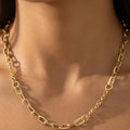 Gold-tone chain link necklace worn on a model, featuring elongated links and finer chain sections