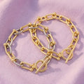 Gold-tone and mixed-tone chain link toggle bracelets with rounded accents on lavender fabric