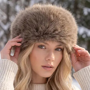 Model wearing a fluffy brown faux fur Cossack style hat with a cream knit sweater outdoors