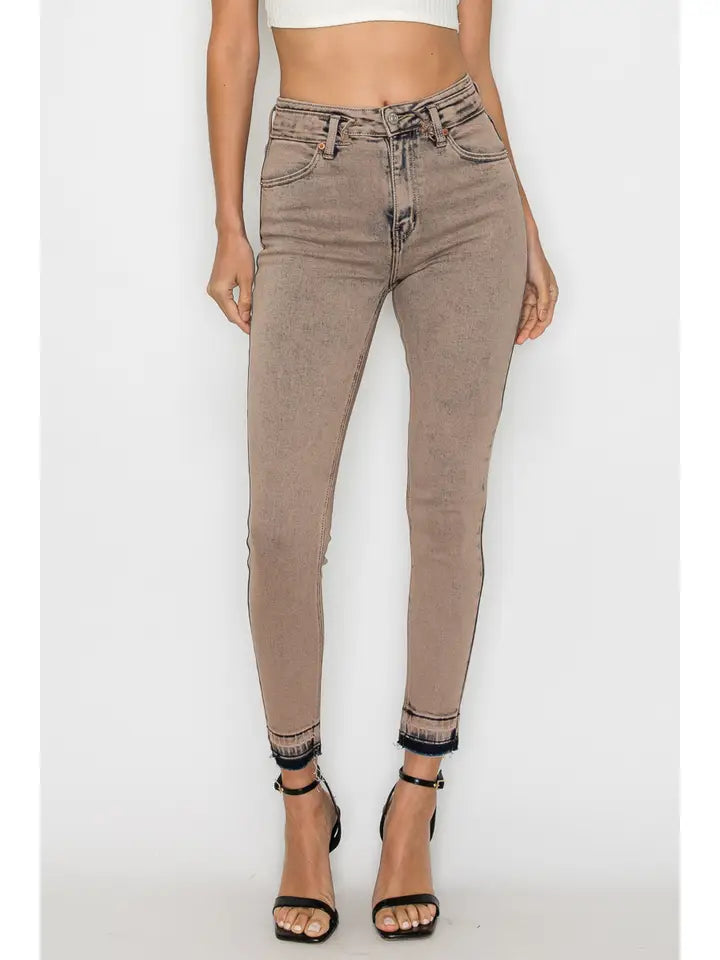Model wearing washed taupe high-rise skinny jeans with a white top and black heels.