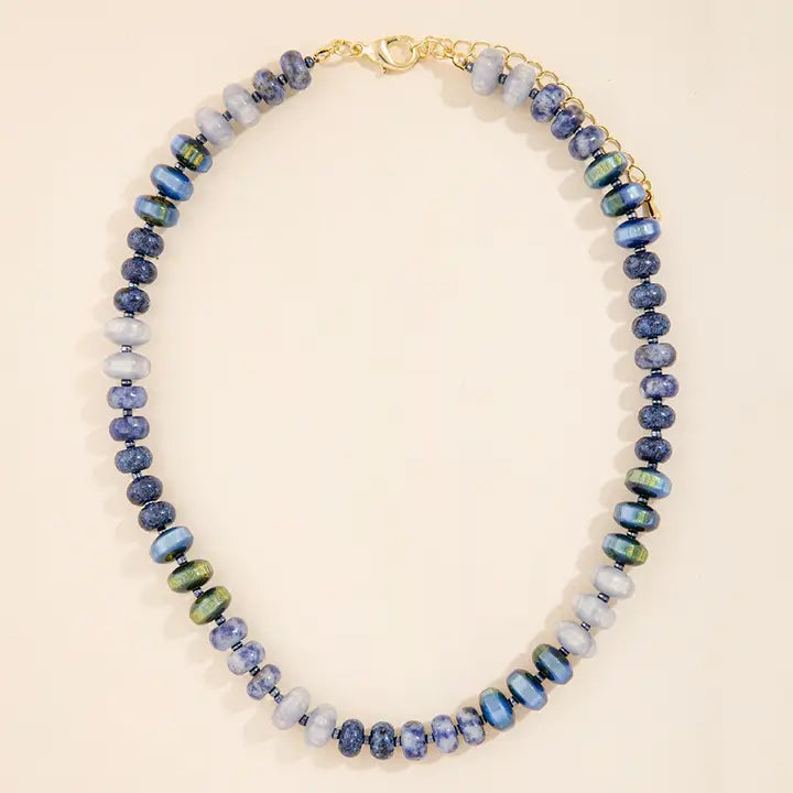 Mixed-bead necklace in blue, lavender, pale neutral, and iridescent green tones with a gold-tone clasp and extender