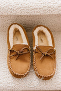 Tan moccasin slippers with cream-colored fluffy lining, stitched toes, and bow details
