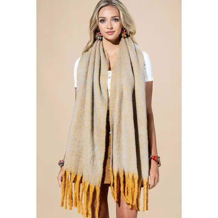 Model wearing a neutral-toned brushed scarf with long mustard-yellow fringed ends