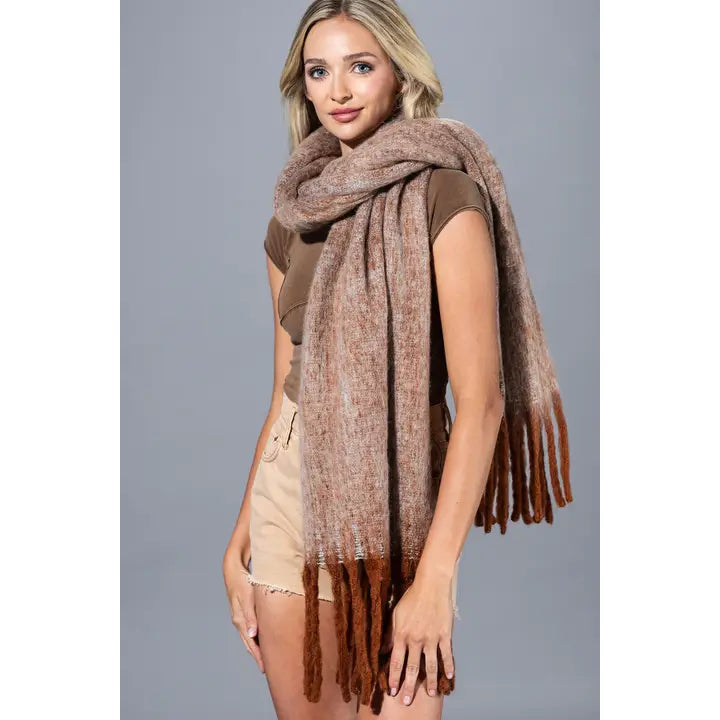 Model wearing a brushed scarf in earthy tones with long rust-colored fringed ends