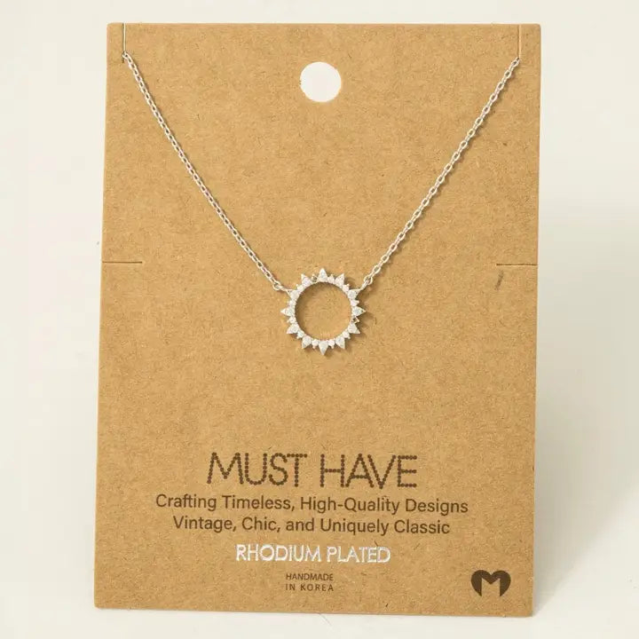 Silver-colored rhodium plated pave sun pendant necklace on a kraft display card