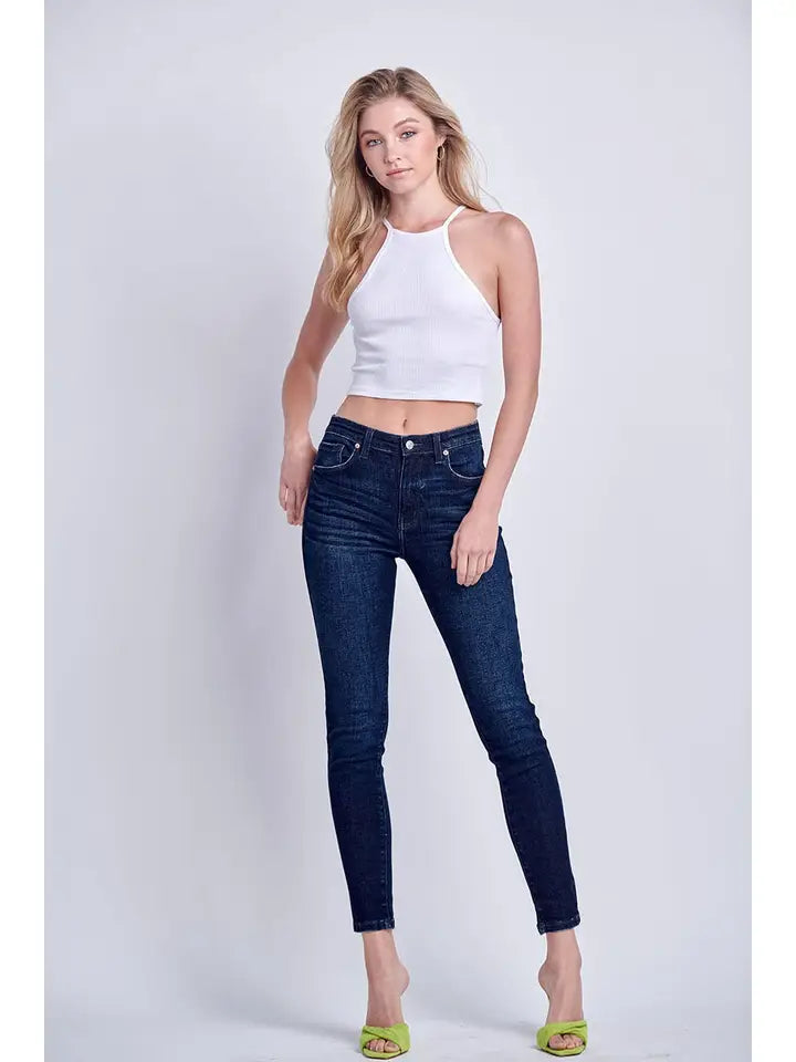 Model wearing Artemis Vintage dark wash skinny jeans with a white sleeveless top.
