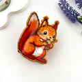 Squirrel Claw Clip shaped like an illustrated red squirrel holding an acorn in warm russet orange and chestnut red acetate