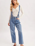 Blue denim suspender jeans with wide legs and front seam detailing, styled with a cream long-sleeve top.