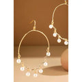 Gold-tone open teardrop earrings with dangling white pearl charms and hook closures