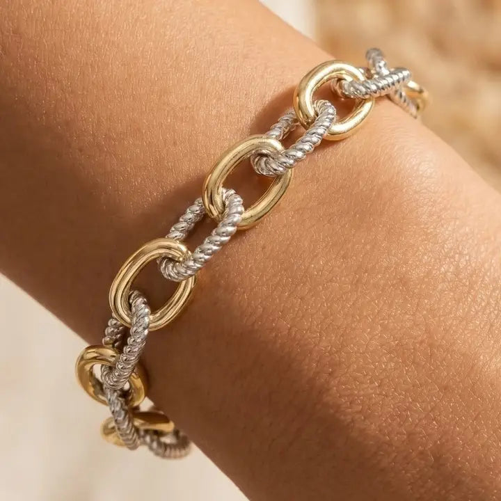 Two-tone bracelet worn on a wrist with smooth gold-tone oval links and silver-tone rope-textured links