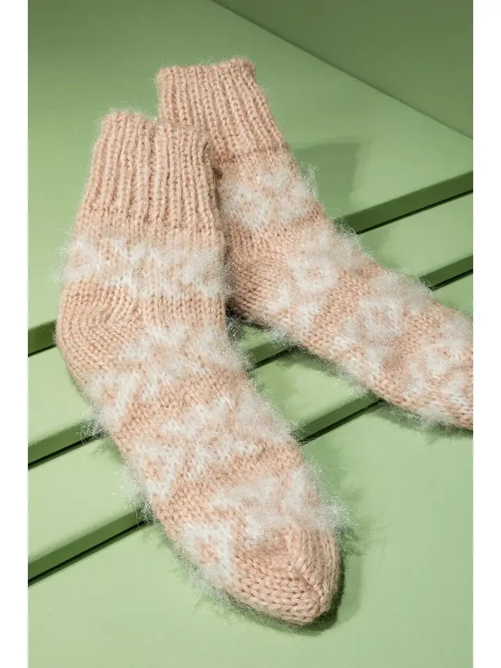 Fuzzy Nordic knit socks in blush and cream on a green surface