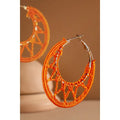 Orange crochet knit hoop earrings on warm neutral background