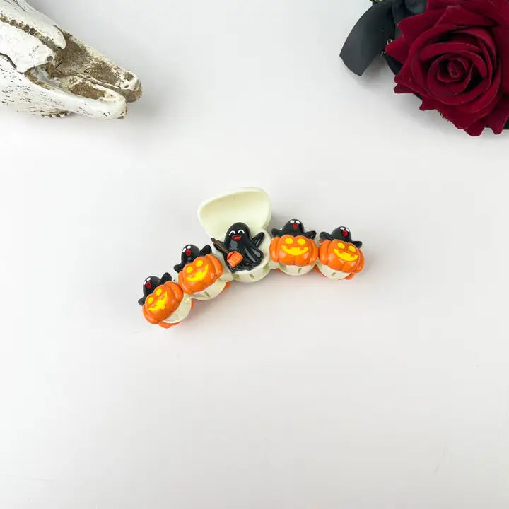 Black Ghost Pumpkin Party Claw Clip with raised 3D black ghost and glowing orange jack-o-lantern charms on cream white base