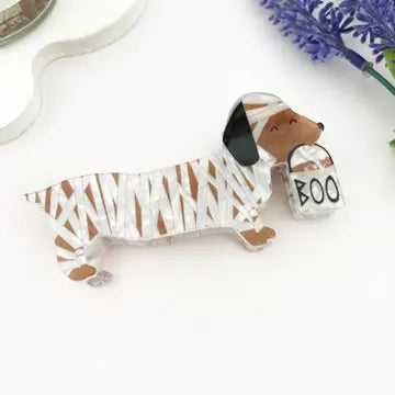 Mummy Dog Claw Clip featuring a dachshund wrapped in mummy bandages holding a BOO trick-or-treat bag