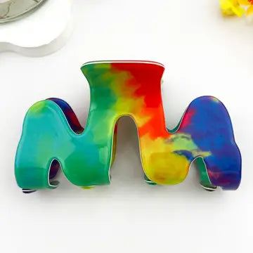 Colorful Wavy Claw Clip in bold three-arch cutout silhouette with swirling rainbow tie-dye blend of teal, green, yellow, red, orange, and deep blue acetate