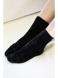 Cozy black chenille socks worn on a neutral background