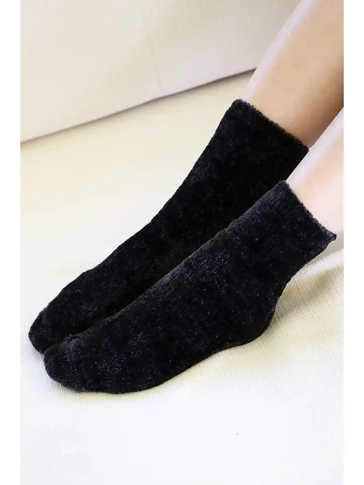 Cozy black chenille socks worn on a neutral background