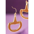 Faux leather and gold horse bit drop earrings on purple background