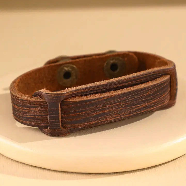 Rustic brown distressed leather cuff bracelet with snap closure on neutral display