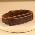 Rustic brown distressed leather cuff bracelet with snap closure on neutral display